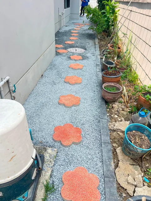 ทางเดินข้างบ้านโรยหินเกล็ด วางแผ่นทางเดินรูปดอกไม้สีส้ม